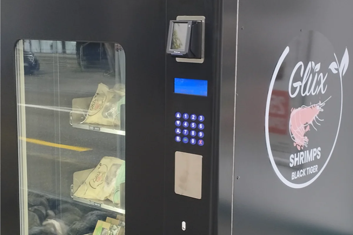 Bedienfeld des Glüx-24/7-Automaten mit Kartenleser, Display und Tastenfeld, dahinter die Fächer mit GlüxShrimps